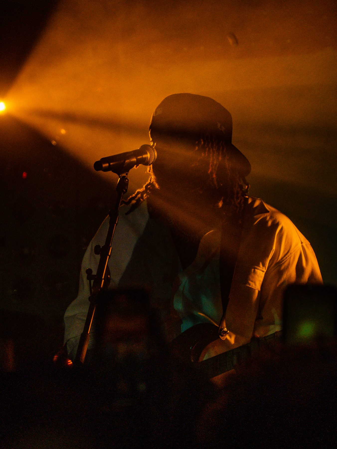 A performer at the microphone dissolving into amber stage haze