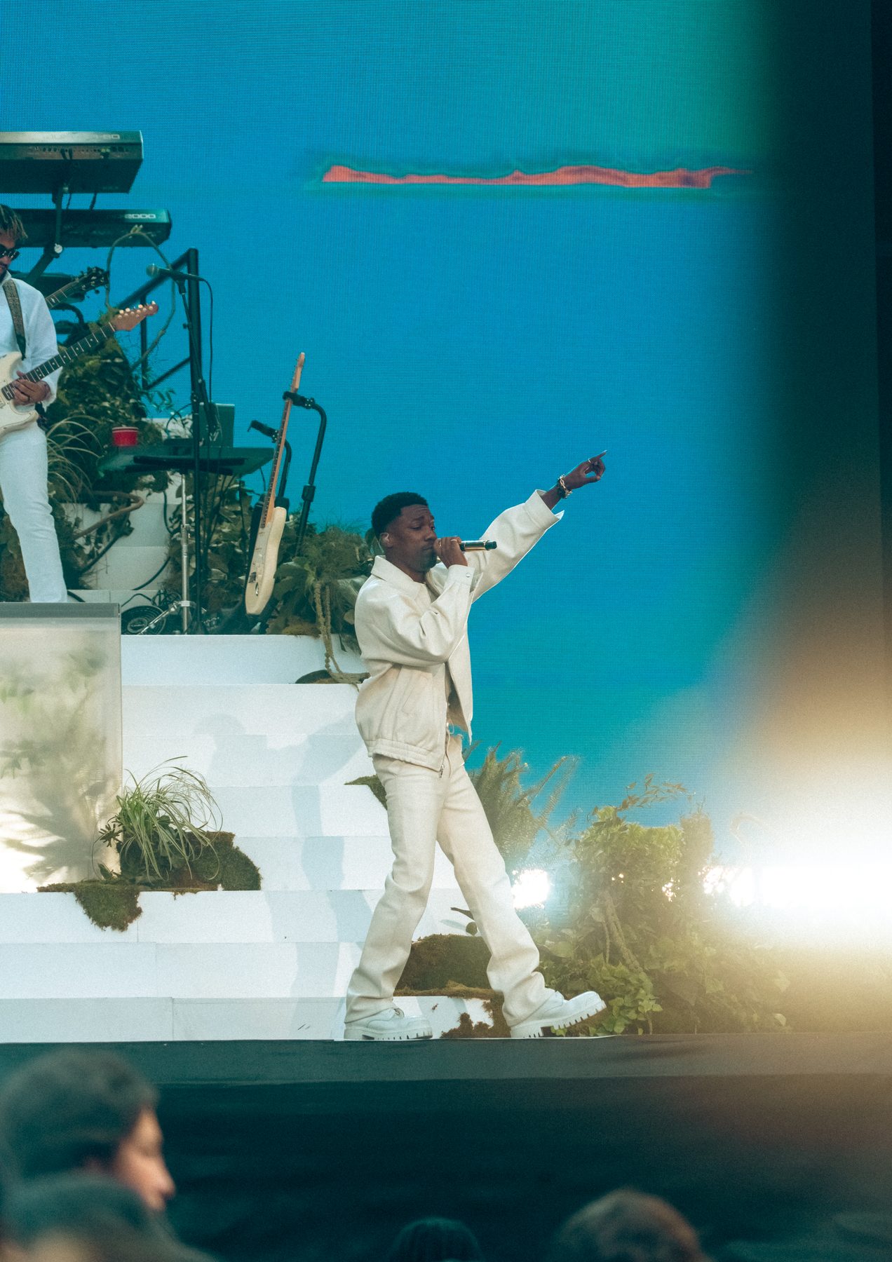 A singer in white pointing out at the audience against a blue backdrop