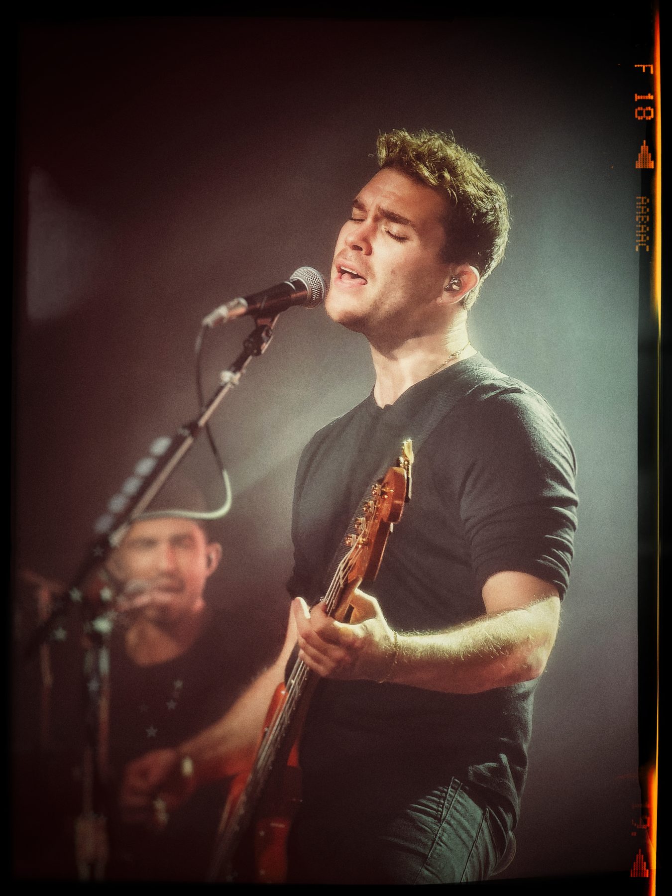A singer at the microphone mid-phrase, bass in hand, eyes closed